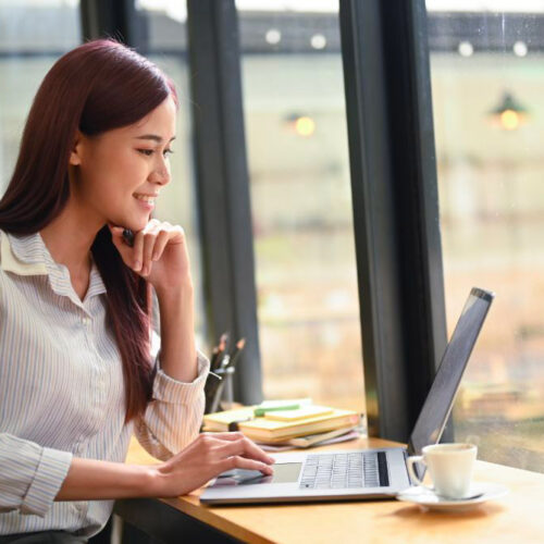 Femme freelance heureuse devant son ordinateur car elle a fait appel à un comptable à Bruxelles