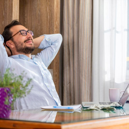 Homme détendu assis à son bureau car il a délégué sa comptabilité