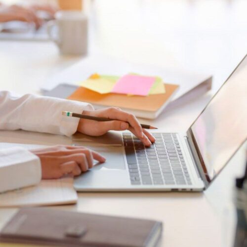 Comptable travaillant sur son ordinateur et remplissant des documents à la main