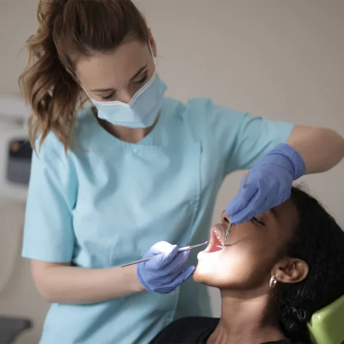 Dentiste qui travaille dans la bouche d'une patiente